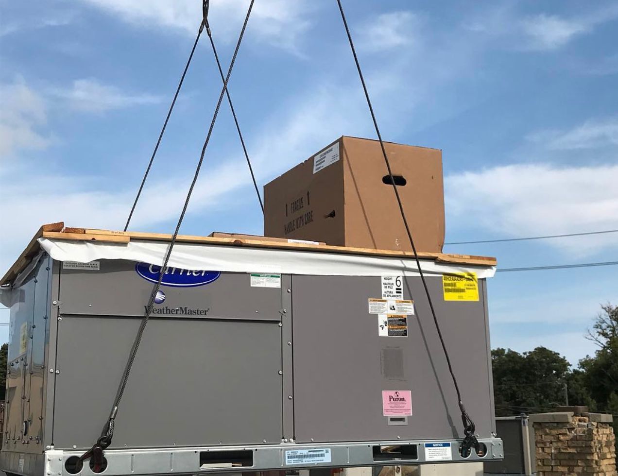 Carrier WeatherMaster rooftop unit being crane-lifted for installation on a Scarborough commercial building