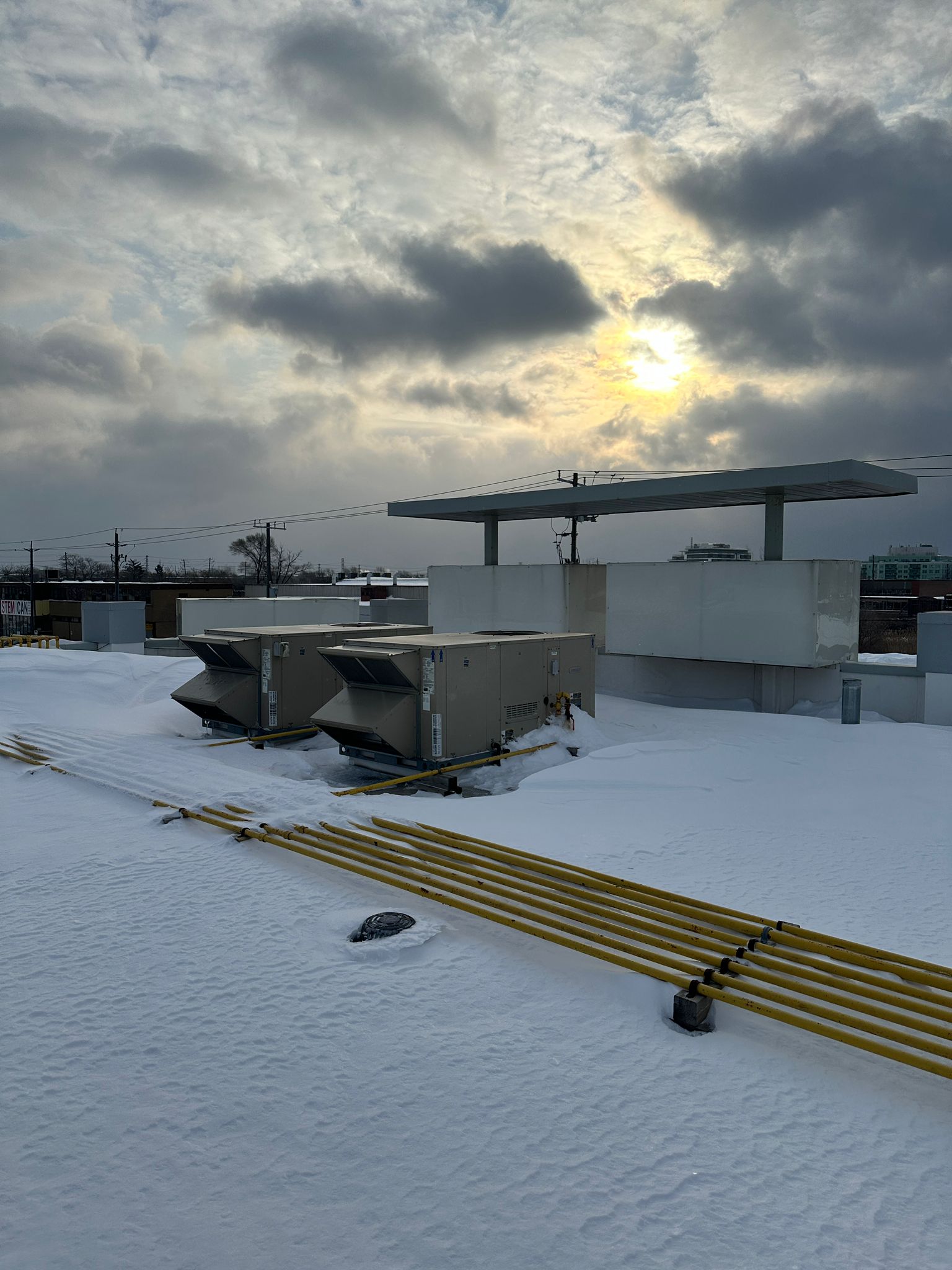 Commercial rooftop HVAC units operating on a snow-covered building roof during a Whitby winter