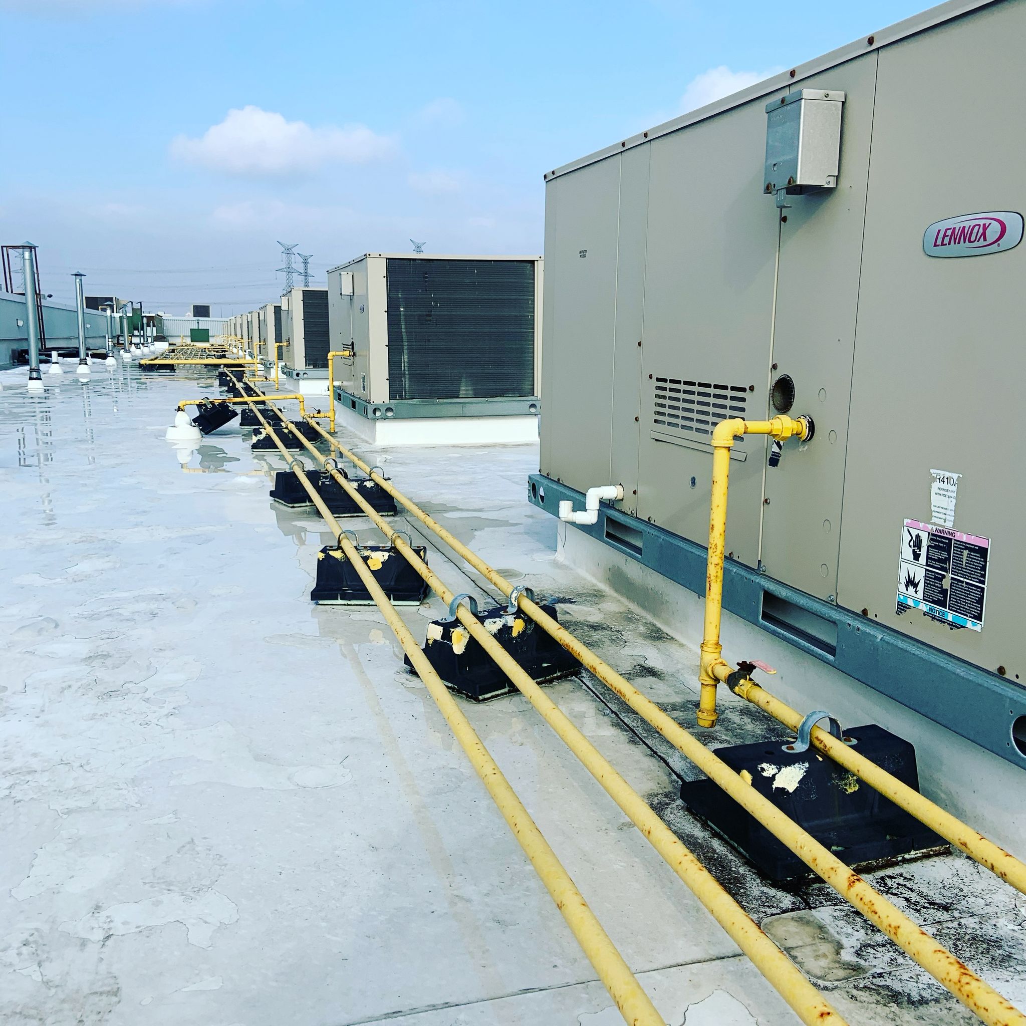 Row of Lennox commercial rooftop units with gas lines on a Toronto commercial building roof