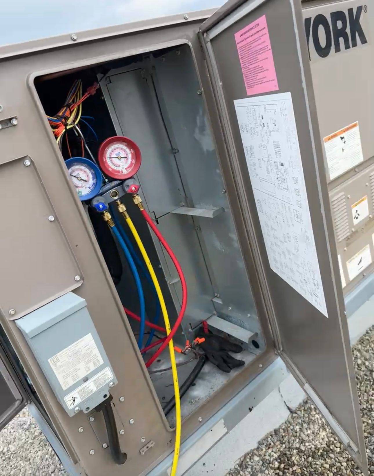 York rooftop unit open with refrigerant gauges connected during service at an Ajax commercial building